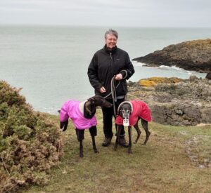 Tracy standing with her 2 dogs on a clifftop.