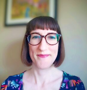 Woman with brown bob and glasses. She is smiling.